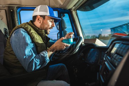 Lastwagenfahrer macht Pause von langer Fahrt, um Lebensmittel aus Container zu essen.