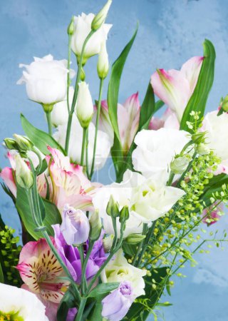 Foto de Ramo de flores elegantes con Lisianthus blanco y púrpura, Alstroemeria y tallos decorativos de primer plano sobre fondo azul texturizado - Imagen libre de derechos