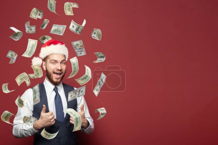 Téléchargez les photos : Père Noël homme d'affaires faisant la pluie de l'argent sur fond rouge - en image libre de droit