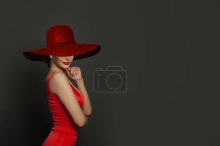 Foto de Hermosa mujer en rojo amplio sombrero de ala ancha sobre fondo gris - Imagen libre de derechos