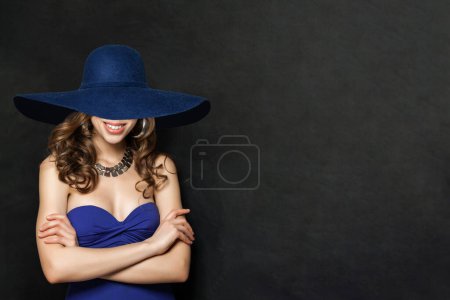 Foto de Retrato de moda de mujer sonriente en vestido azul y sombrero azul ancho, niña con cabello rizado - Imagen libre de derechos