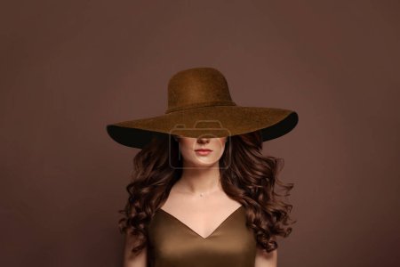 Foto de Hermoso modelo de pelo rizado en sombrero de ala ancha marrón. Mujer con peinado largo ondulado y retrato de sombrero. - Imagen libre de derechos