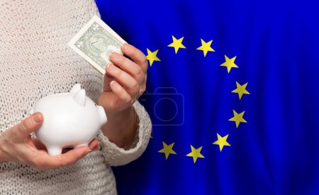 Téléchargez les photos : European woman with money bank on the background of EU flag. Dotations, pension fund, poverty, wealth, retirement concept - en image libre de droit