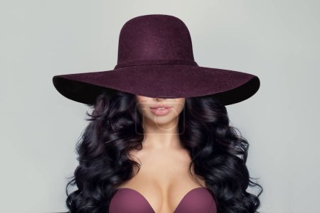 Foto de Hermosa mujer modelo con peinado rizado en sombrero de ala ancha púrpura - Imagen libre de derechos