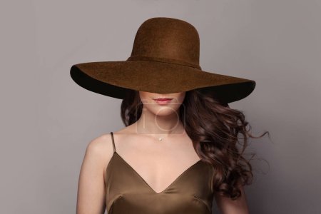 Foto de Mujer morena con el pelo ondulado en amplio sombrero de ala ancha marrón. - Imagen libre de derechos