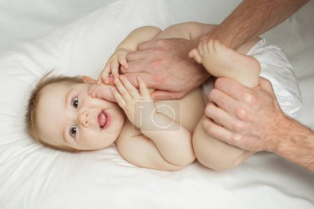 Téléchargez les photos : Mignon heureux 7 mois bébé fille dans couche mensonge et jouer - en image libre de droit