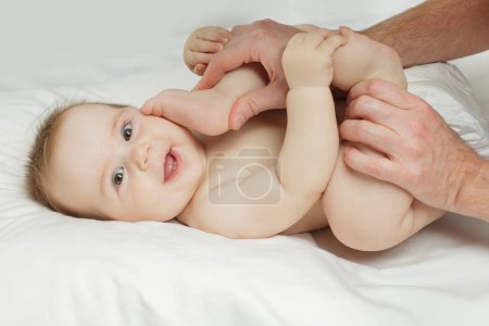 Téléchargez les photos : Adorable bébé souriant et allongé sur le lit - en image libre de droit