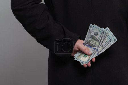 Téléchargez les photos : Un homme d'affaires qui cache de l'argent derrière son dos. Personne d'affaires avec billet en argent comptant en dollars américains - en image libre de droit