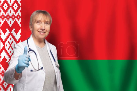 Belarussian smiling mature doctor woman holding stethoscope on flag of Belarus background