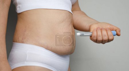 Self injection. Female model with injection pen close up. Medicine and treatment concept