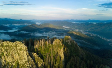 Téléchargez les photos : Sommet rocheux de la chaîne de montagnes couvert de forêt d'épinettes dans la vallée du soir brumeux des montagnes Rhodopes sous le coucher du soleil ciel nuageux - en image libre de droit