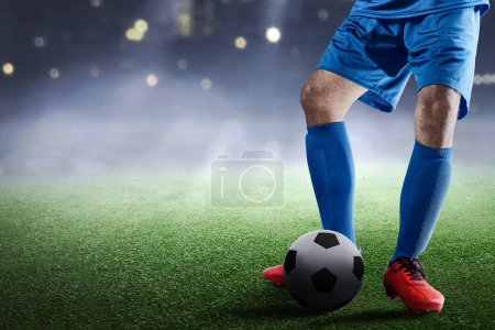 Foto de Jugador de fútbol hombre en una camiseta azul de pie con la pelota en el campo de fútbol - Imagen libre de derechos