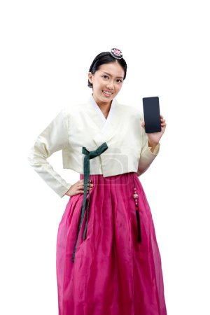 Photo for Asian woman wearing a traditional Korean national costume, Hanbok, standing while showing empty screen on mobile phone isolated over white background - Royalty Free Image