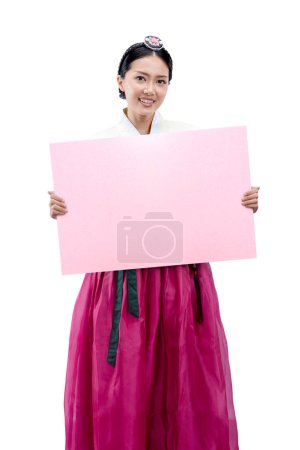 Foto de Mujer asiática vestida con un traje nacional coreano tradicional, Hanbok, de pie mientras sostiene papel vacío para espacio de copia aislado sobre fondo blanco - Imagen libre de derechos