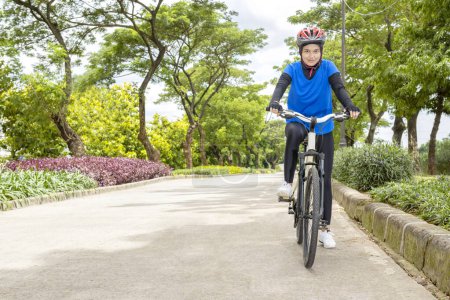 Mujer asiática con un paseo en bicicleta casco en el parque