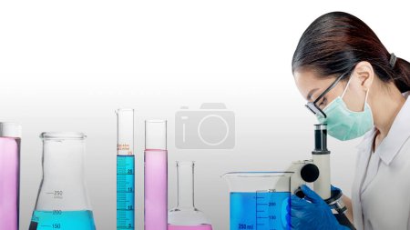 Foto de Científicas asiáticas usando un microscopio con coloridos químicos en cristalería de laboratorio. Día Nacional de la Ciencia - Imagen libre de derechos