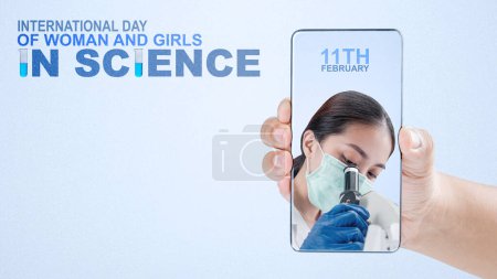 Téléchargez les photos : Des mains humaines tenant des téléphones portables avec un écran de scientifiques asiatiques utilisant des microscopes avec un fond coloré. Journée internationale des femmes et des filles en science - en image libre de droit