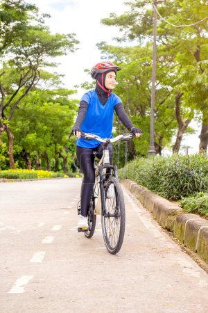 Mujer asiática con un paseo en bicicleta casco en el parque