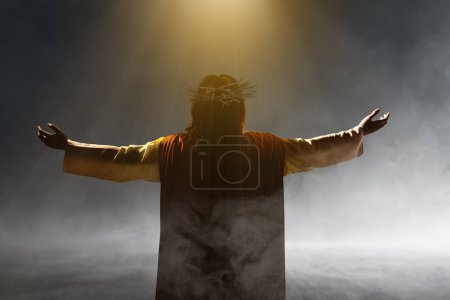 Photo for Rear view of Jesus Christ with a crown of thorns raised hands and praying to god with a sunset sky background - Royalty Free Image
