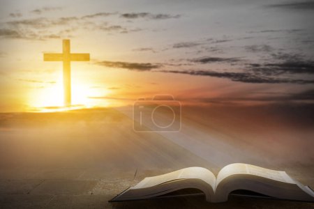 Téléchargez les photos : Croix chrétienne et livre ouvert avec un fond de scène de coucher de soleil - en image libre de droit