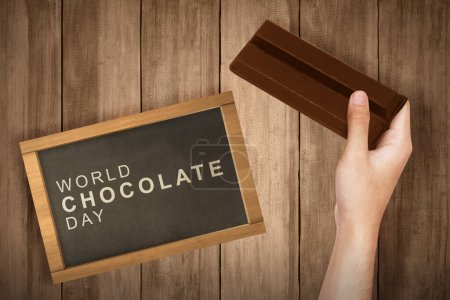 Human hand holding the chocolate bar. World chocolate day concept