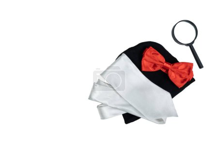 Sombrero negro, lupa y pajarita roja con corbata plateada aislada sobre fondo blanco