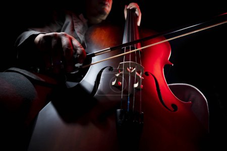 Téléchargez les photos : Musicien jouant du violoncelle. Violoncelliste ou violoncelliste jouant avec un fond noir - en image libre de droit