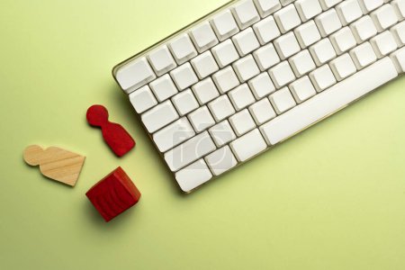 Téléchargez les photos : Closeup view of a computer keyboard with a wooden cube and wooden figure on a colored background - en image libre de droit