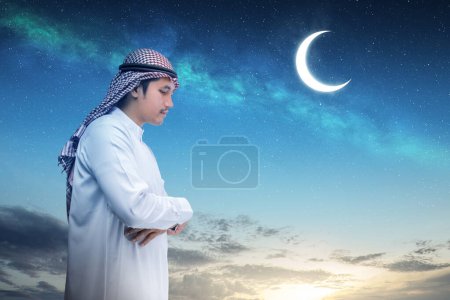 A Muslim man with agal in a praying position (salat) with a night scene background. Muslim concept