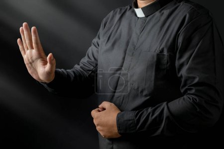 Foto de Retrato de un pastor dando un sermón sobre un fondo negro. Concepto cristiano - Imagen libre de derechos