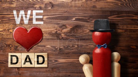 Foto de Red wooden peg doll with a black hat and bow tie with a red heart and We Love Dad text. Fathers day concept - Imagen libre de derechos