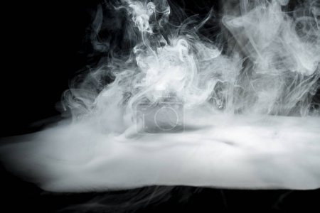 Téléchargez les photos : Fumée blanche tourbillonnante sur un fond sombre. Contexte abstrait - en image libre de droit