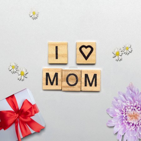 Téléchargez les photos : Cubes en bois avec I Love Mom texte et une boîte cadeau sur un fond blanc. Concept de fête des mères - en image libre de droit