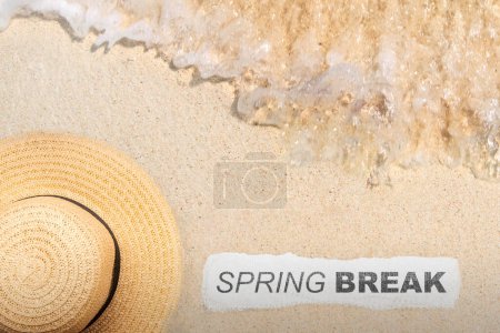 Beach hat and paper with Spring Break text on the sandy beach. Spring break concept