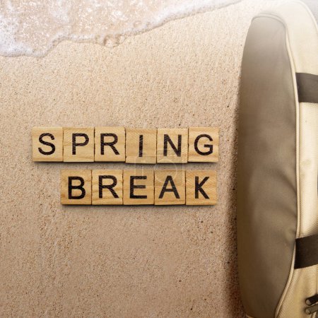 Tasche und Holzwürfel mit Spring Break Text am Sandstrand. Frühjahrspause-Konzept