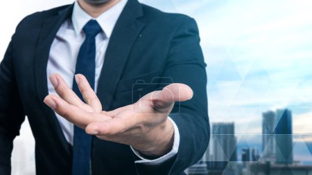 Foto de Portrait of a confident businessman posing with open palm hand with a cityscape background - Imagen libre de derechos