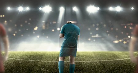 Photo for Portrait of a male football player celebrating his win on the pitch with spotlights background - Royalty Free Image