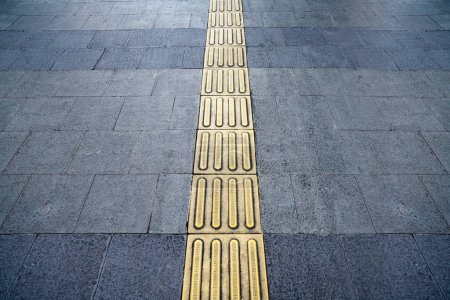 Foto de Sendero con pavimento táctil amarillo para personas ciegas caminando con seguridad en la acera en Yakarta, Indonesia - Imagen libre de derechos