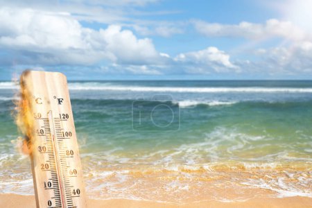 High temperature weather on summer seasons. Image of burned thermometer on a beach with sunbeam. Climate exchange concept.