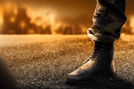 Foto de Pies de soldado con botas militares de pie con fuego y explosión en el fondo de la escena de guerra - Imagen libre de derechos