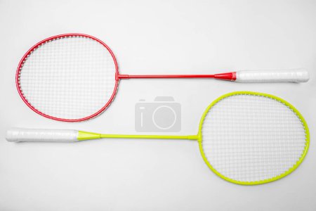 Overhead view of two colorful badminton rackets with red and yellow frames and white grips, isolated on a clean white background, with space for text or design elements