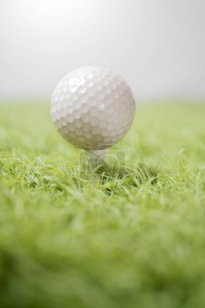 Primer plano detallado de una pelota de golf colocada sobre un fondo centrado en el softfocus, destacando la textura de la pelota sobre una superficie cubierta de hierba verde brillante