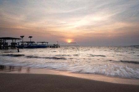 The ocean is calm and the sky is a beautiful orange color. The sun is setting and the water is reflecting the colors of the sky. Pantai kartini beach