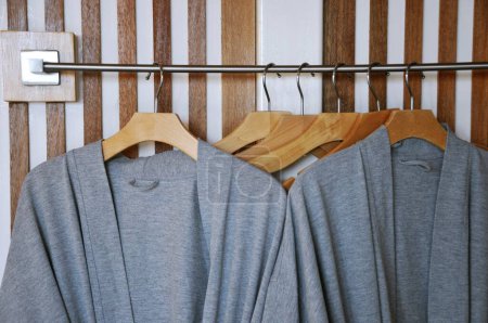 Photo for Modern wooden wardrobe with clothes hanging on rail in walk in closet, Choice of fashion clothes of different colors on wooden hangers - Royalty Free Image