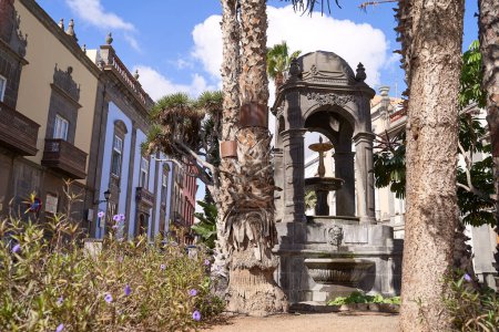 Photo for Outdoor fountain with medieval architecture and palm trees at Plaza del Espiritu Santo in Vegueta, Las Palmas de Gran Canaria, Spain - Royalty Free Image