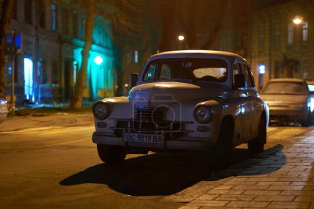 Téléchargez les photos : Lviv, Ukraine - 01 déc. 2017 : La vieille voiture rétro GAZ M20 Pobeda sort vers 1950 en URSS garée dans la rue de la ville nocturne - en image libre de droit
