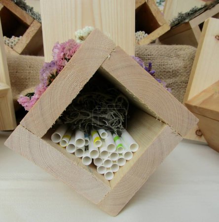 Téléchargez les photos : Insect hotels made of wooden boards, paper straws and moss, decorated with dried natural flowers - en image libre de droit