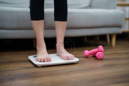 Foto de Dieta grasa y pies de balanza de pie en balanzas electrónicas para el control de peso. Instrumento de medición en kilogramo para un control de la dieta. - Imagen libre de derechos