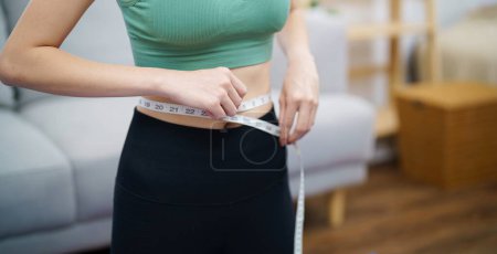 Foto de Mujer asiática con anorexia con cinta métrica sintiéndose infeliz. Problema de anorexia percepción corporal y dismorfia - Imagen libre de derechos