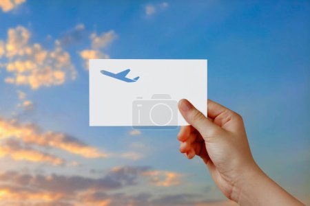 Photo for Man's hand holding airplane symbol paper in sky. Concept of journey, travel, dream, freedom. Hand is holding paper airplane against blue sky with empty space for text. - Royalty Free Image